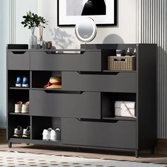 a black dresser with drawers and shoes on it in front of a wall mounted mirror