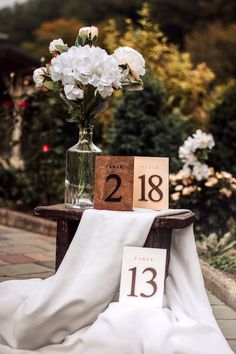 a vase with white flowers sitting on top of a table next to a wooden sign