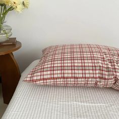 a bed with a red and white checkered pillow on it