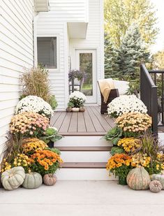 the front porch is decorated with flowers and pumpkins