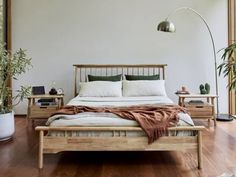 a bed sitting in a bedroom next to a plant on top of a hard wood floor