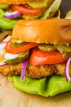 two chicken sandwiches with pickles, tomatoes and onions