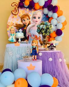 a frozen princess birthday party with balloons, cake and decorations on the table in front of it