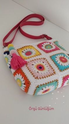 a crocheted purse with tassels on the handles and handle is sitting on a white surface