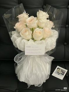 a bouquet of white roses sitting on top of a black leather chair next to a card