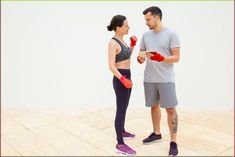 a man and woman standing next to each other with boxing gloves on their hands, looking at each other