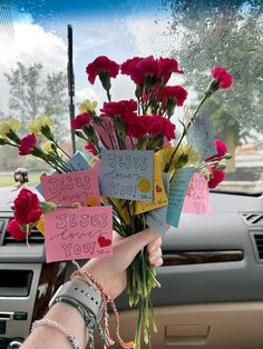 a person holding flowers in their hand with notes attached to it and the words jesus loves you written on them