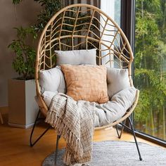 a chair that is sitting in front of a window with pillows on top of it