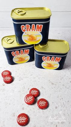 three tins filled with cream sitting on top of a white counter next to red and yellow candies