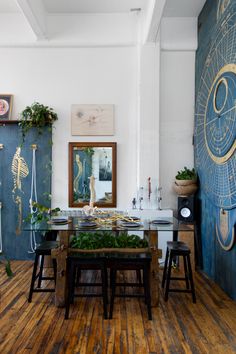 a dining room with wooden floors and blue painted wall behind the table, surrounded by potted plants