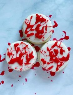 three cupcakes with red and white icing on them sitting on a marble surface