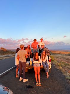 a group of people sitting on the back of a pick up truck in front of a road