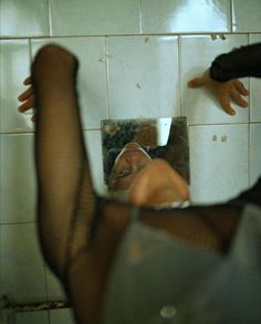 a woman in fishnet stockings looking at her reflection in the mirror with her leg up