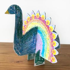 a colorful paper peacock sitting on top of a wooden table