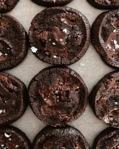 chocolate cookies with white sprinkles are arranged on a baking sheet, ready to be eaten