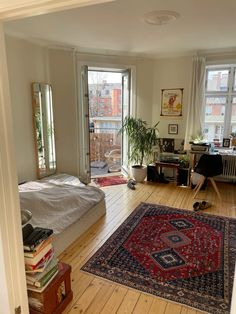 a living room filled with furniture and lots of windows next to a bed covered in blankets