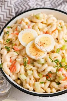 a bowl filled with macaroni salad and two boiled hard boiled eggs on top