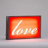 a red light with the word love lit up in white letters on an orange background