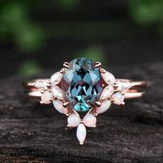 a blue and white diamond ring on top of a piece of wood with leaves around it