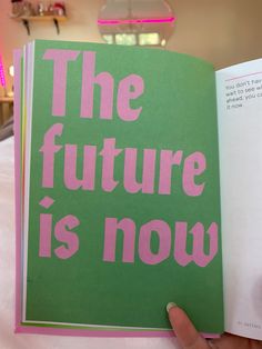 a person holding up a book with the words the future is now