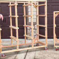 two wooden frames sitting on wheels in front of a garage