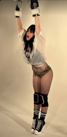 a woman in fishnet stockings and knee high boots is posing for the camera with her hands up