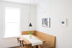 a dining room table and bench with flowers in a vase on the table next to it