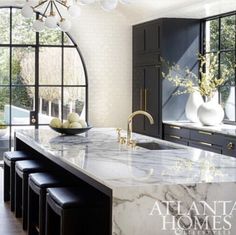 a large kitchen with marble counter tops and black cabinetry is featured in atlanta homes magazine