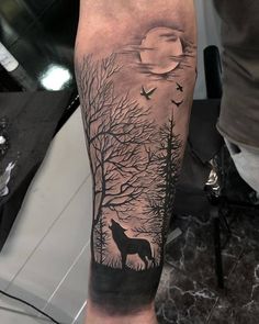 a man's arm with a wolf and trees tattoo on it