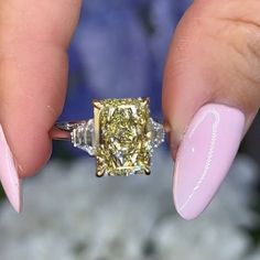 a woman's hand holding a yellow diamond ring