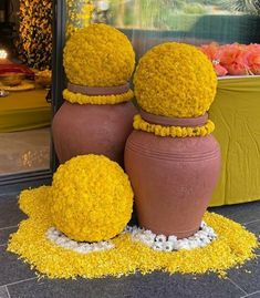 three vases with yellow flowers on the ground