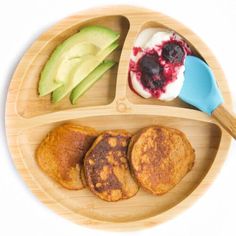 a wooden plate topped with three different types of breakfast foods next to an avocado