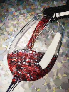 a wine glass filled with red liquid sitting on top of a mosaic tile tablecloth