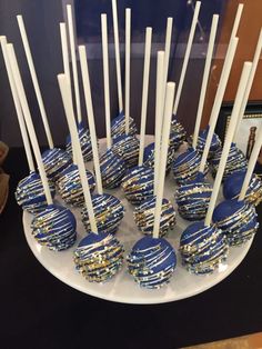 blue and gold cake pops on a plate with white sticks sticking out of the top