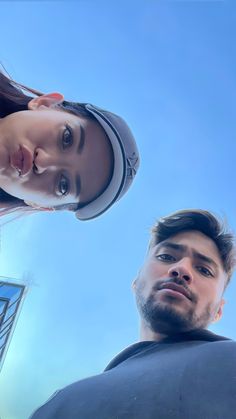 two people standing next to each other in front of a building with a sky background