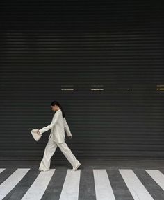 a woman walking across a cross walk in front of a garage door