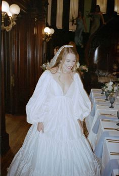 a woman in a wedding dress standing next to a table with place settings on it