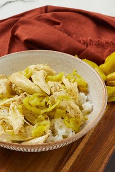 a bowl filled with chicken and rice on top of a wooden table