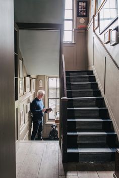 an older man is standing at the bottom of stairs with his dog in front of him