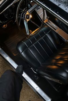 the interior of an old car with black leather seats and steering wheel, seen from above