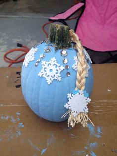 a blue pumpkin decorated with snowflakes and braids on it's side