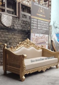 an ornate wooden couch sitting in front of a brick wall with a sign on it