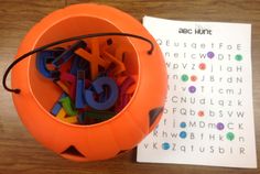 an orange plastic container filled with letters on top of a wooden table next to a piece of paper