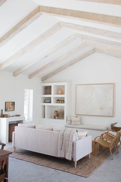 an instagram photo of a living room with white furniture and wood beams on the ceiling