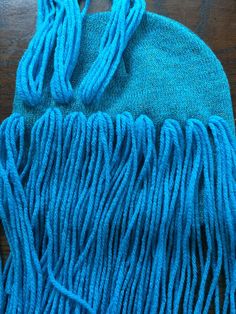 a close up of a blue bag on a wooden table with some tassels