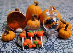 there are many small pumpkins on the table with candy sticks in front of them