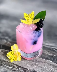 a pink cocktail with blackberries and yellow flowers