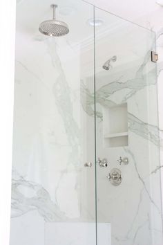 a bathroom with marble walls and floor, shower head and hand held faucet