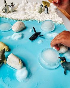 a child's hand reaching for an ice ball on top of a blue cake