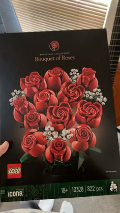 a hand holding up a lego bouquet of roses box with flowers in it's front